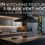 A modern kitchen featuring a bold matte black vent hood against a white tile backsplash with gold hardware accents.