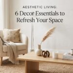 A beautifully styled living room featuring textured throw pillows, symmetrical ceramic table lamps, and delicate cherry blossom branches arranged in a tall floor vase.