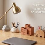 A digitally optimized, high-contrast flat lay featuring a 3D engraved moon paperweight, a quirky astronaut mug, and a sleek vertical pen organizer on a modern wooden desk.